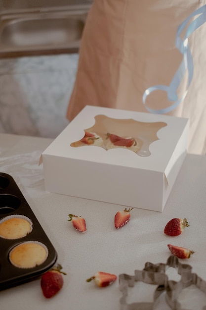 女性の子屋は自家製のカップケーキを展示する顧客に配送するためのパッケージにカップケーキをめ込みます