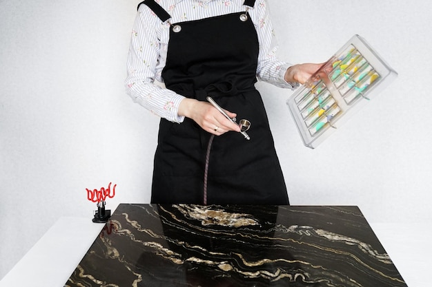 Female pastry chef sprays food paint with a pastry airbrush