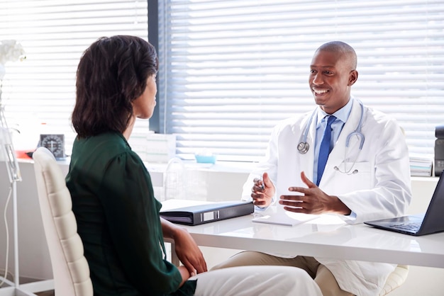 Female Patient In Consultation With Doctor Sitting At Desk In Office