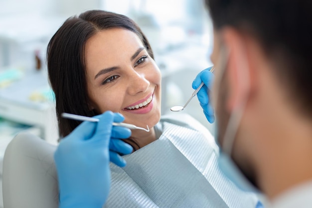 Female patient at dental procedure doctor using dental instruments in modern dental clinic