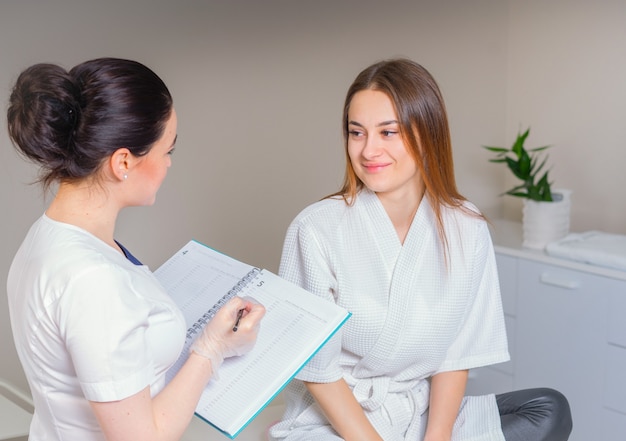 Medico e paziente femminile hanno consultazione nella clinica medica, scrivere note