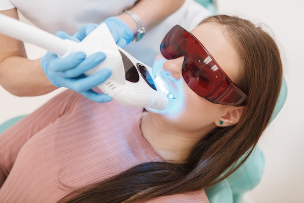 Female patient getting dental whitening by professional dentist