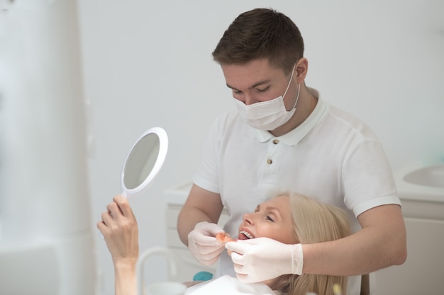 A female patient looking in the mirror at the results of the dental surgery