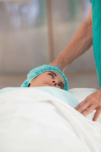 Female patient lying on a bed while looking a surgeon