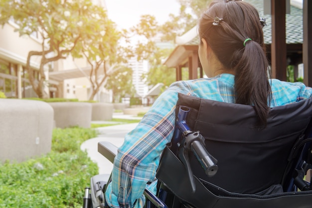 Foto paziente femminile che si siede in una sedia a rotelle nel giardino dell'ospedale