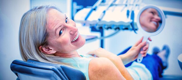 Female patient smiling while holding mirror