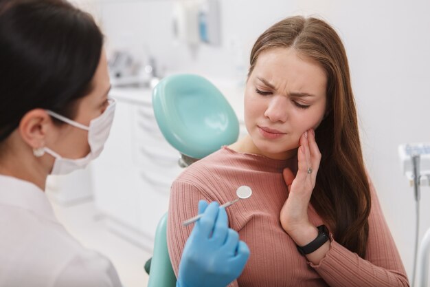 Female patient suffering from toothache sitting ind ental chair