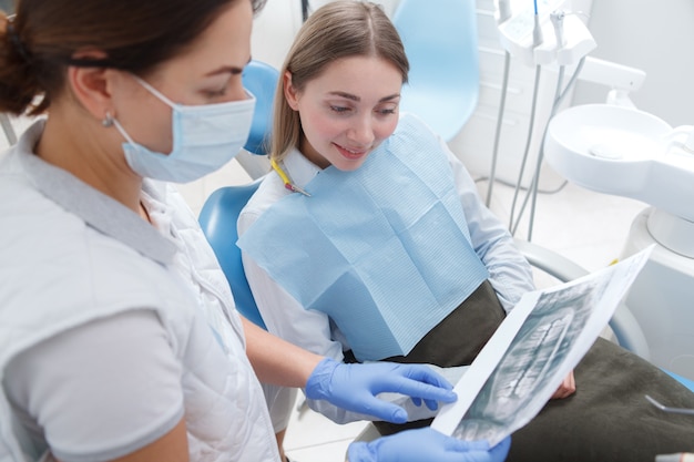 Female patient talking to her dentist, looking at dental x-ray scan