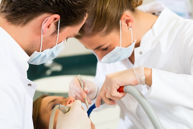 Female patient with dentist and assistanta dental treatment, wearing masks and gloves