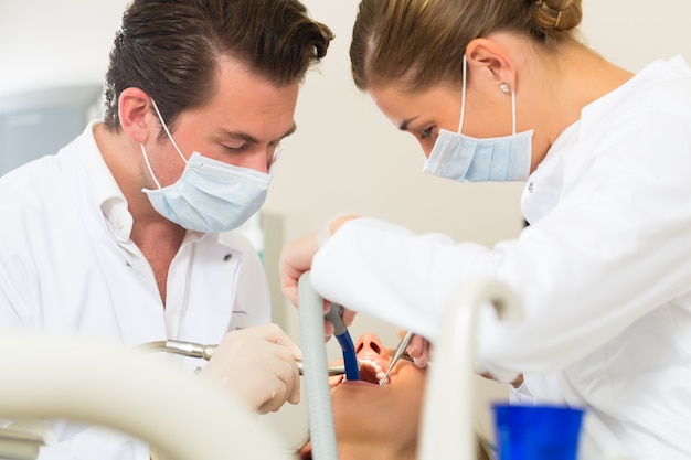 Female patient with dentist and assistanta dental treatment, wearing masks and gloves