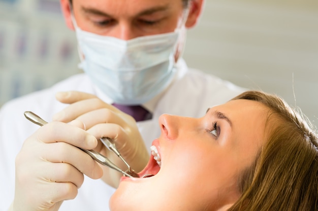 Paziente femminile con trattamento dentistico dentista, indossando maschere e guanti