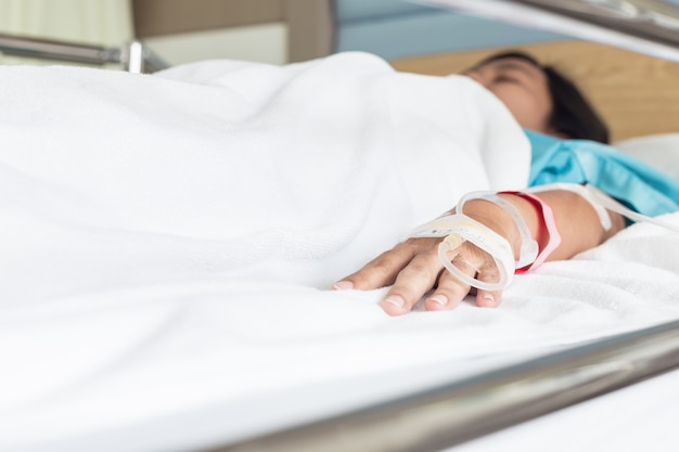 Foto paziente femminile con l'ago del gocciolamento iv che penetra nella stanza di ospedale