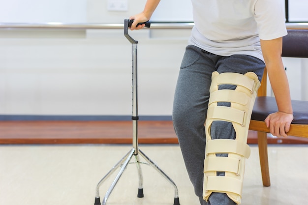 Female patients wear knee support devices to reduce movement while using cane to get up from the chair. 