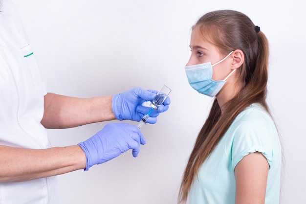 Foto la dottoressa o l'infermiera pediatrica fa un'iniezione o un vaccino alla vaccinazione della ragazza paziente ...