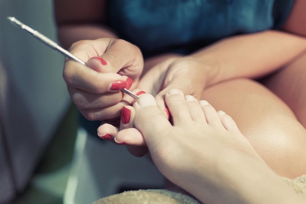 Female pedicure care for feet and toenails master conducts\
procedures for foot care