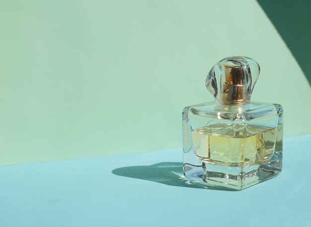 Photo female perfume bottle on a pastel blue background with crystal shadows.