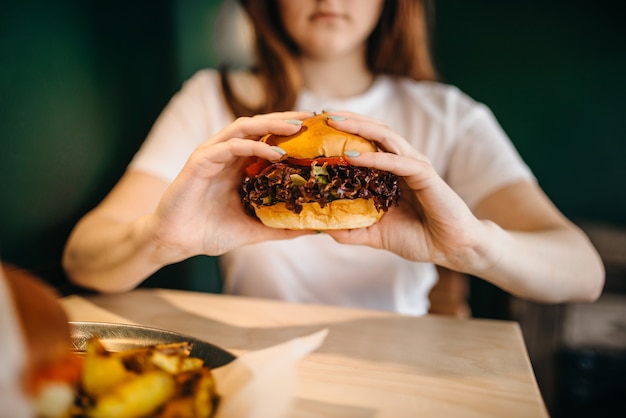 Female person eats fresh burger