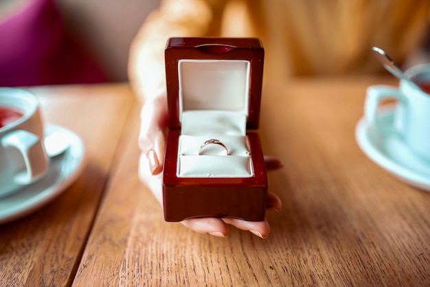 Foto la mano della persona femminile tiene la scatola con la vista del primo piano dell'anello nuziale dorato