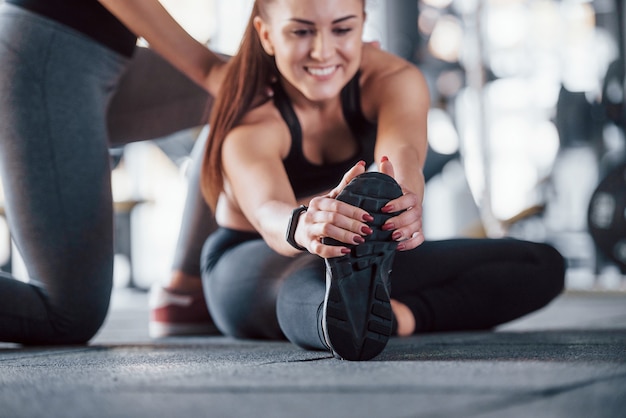 Foto istruttore personale femminile che aiuta la donna a fare esercizi in palestra.