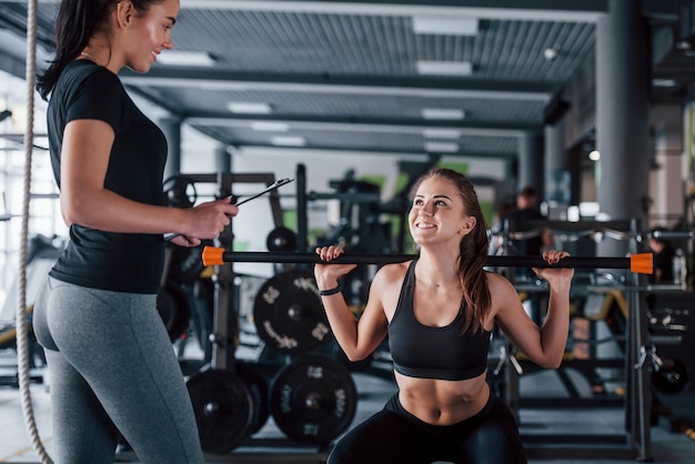 Istruttore personale femminile che aiuta la donna a fare esercizi in palestra.