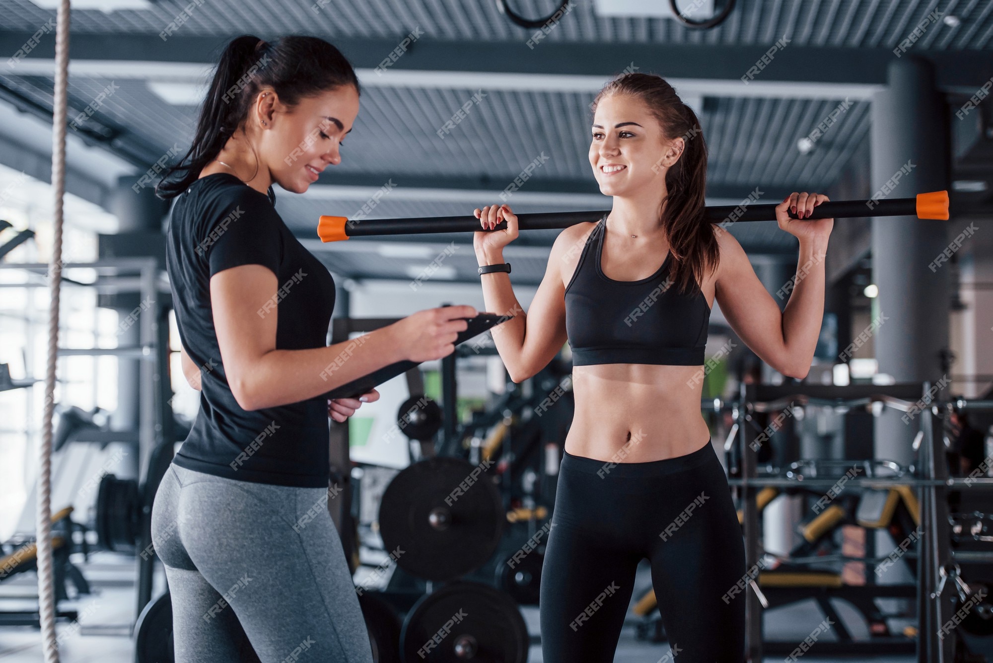 Young Woman Exercising While Her Female Personal Trainer Assisting