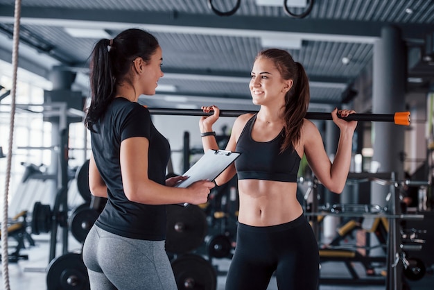 Istruttore personale femminile che aiuta la donna a fare esercizi in palestra.