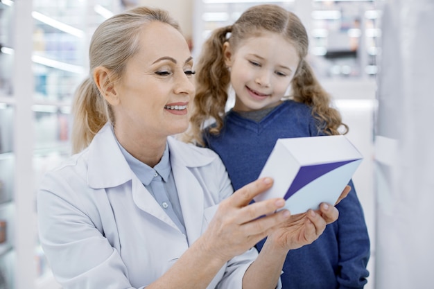 Female pharmacist helping a little girl in a drugstore