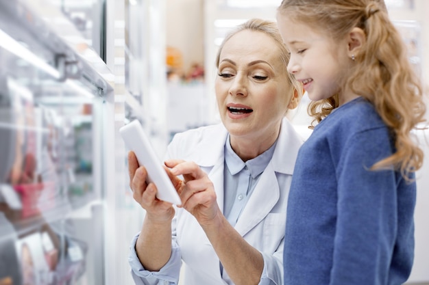 Female pharmacist helping a little girl in a drugstore