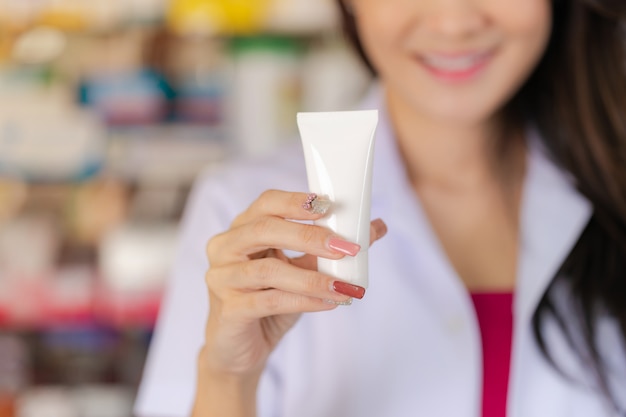 Photo female pharmacist holds medicine tube in the pharmacy