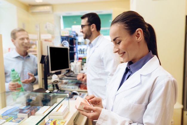 Female pharmacist is considering packaging of pills.