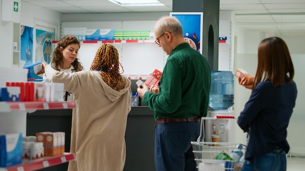 Female pharmacist serving clients with pills and medicaments, scanning medicine products and giving assistance in pharmacy. Medical worker helping people to buy treatment and drugs.