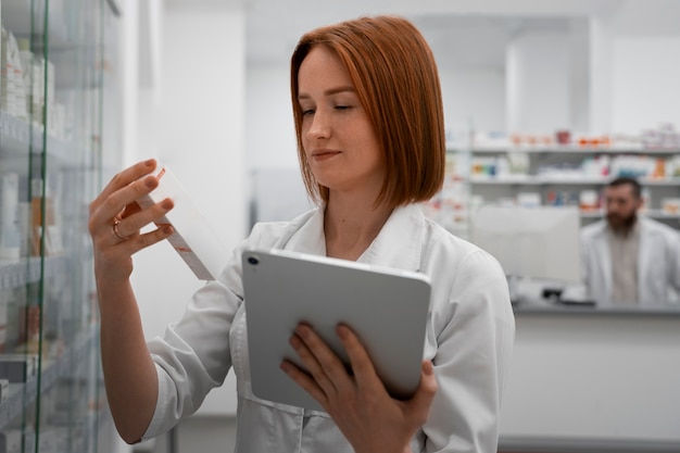 Foto farmacista femminile che lavora con il tablet in farmacia
