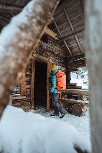 雪に覆われた森の小屋に入る女性写真家