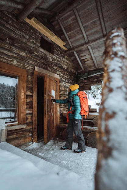 Female photographer entering a cabin in the snowy woods