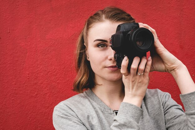 Foto fotografo femminile che tiene una macchina fotografica in ritratto