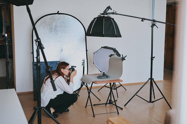 プロの機器で写真スタジオで背景の物体を撮影する女性写真家