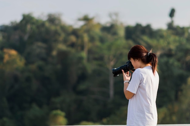 Foto fotografa femminile che scatta foto con uno sfondo naturale