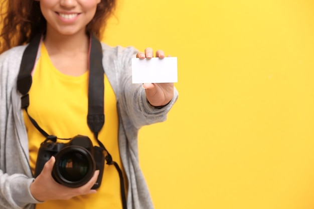 色の背景に名刺を持つ女性写真家