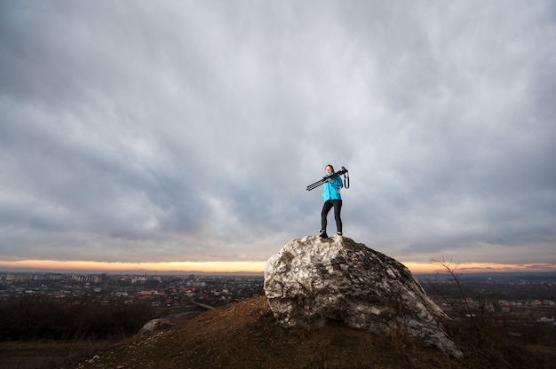 Female photographer with camera on tripod on the big rock