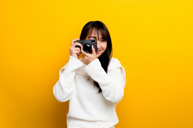 Female photographer with camera young women love taking pictures camera lover taking pictures in the yellow studio