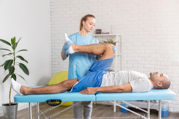 男性の脚の可動性をチェックする女性理学療法士