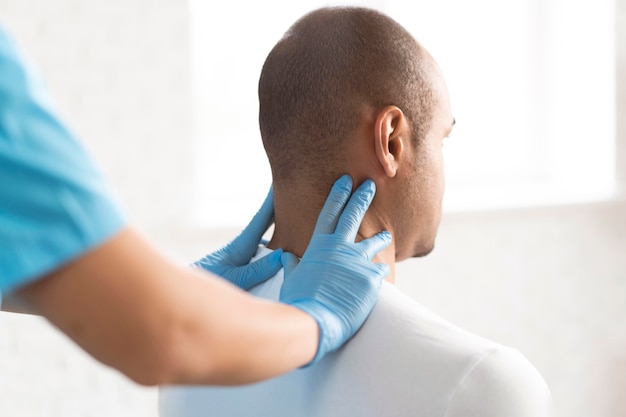 Photo female physiotherapist checking man's neck