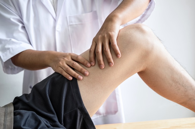 여성 물리 치료사는 남성 환자의 다친 다리 치료 검사, 재활 치료 통증을 클리닉에서 수행하는 작업