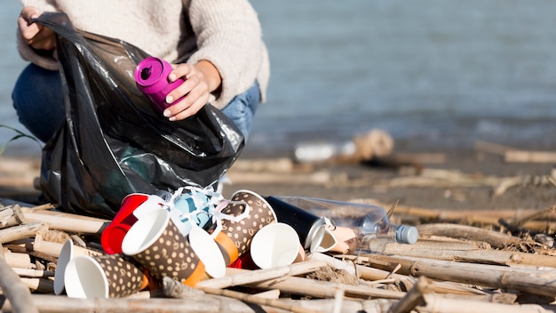 female picking trash from seaside