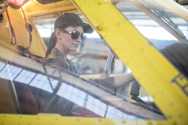 Female pilot inspecting light aircraft cockpit