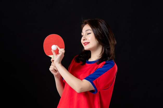 Female player training with racket and ball on dark