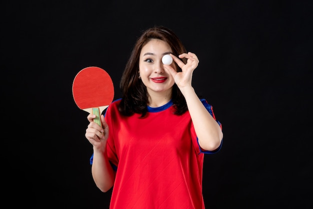 Female player training with racket and ball on dark