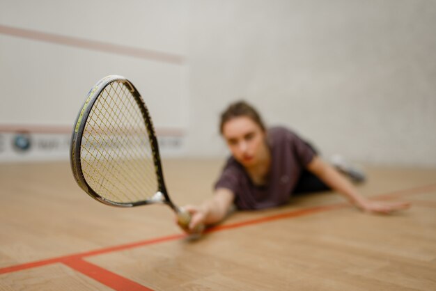 Female player with squash racket lies on the floor. Girl on game training, active sport hobby on court