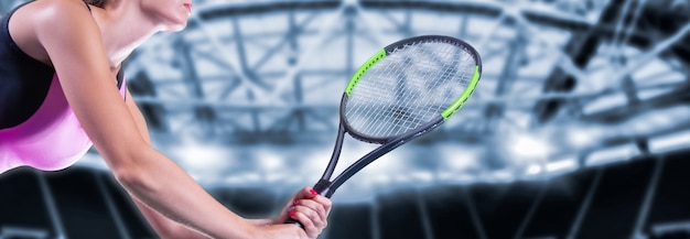テニスラケットとスポーツアリーナの背景を持つ女性プレーヤー