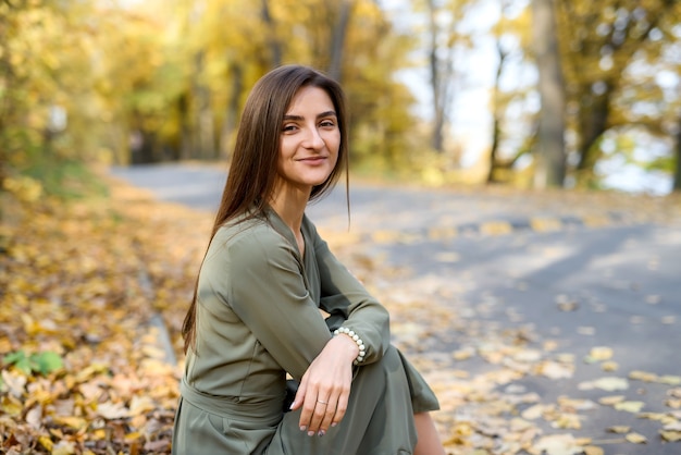 Female portrait. Brunette woman portrait in autumn park wearing olive dress